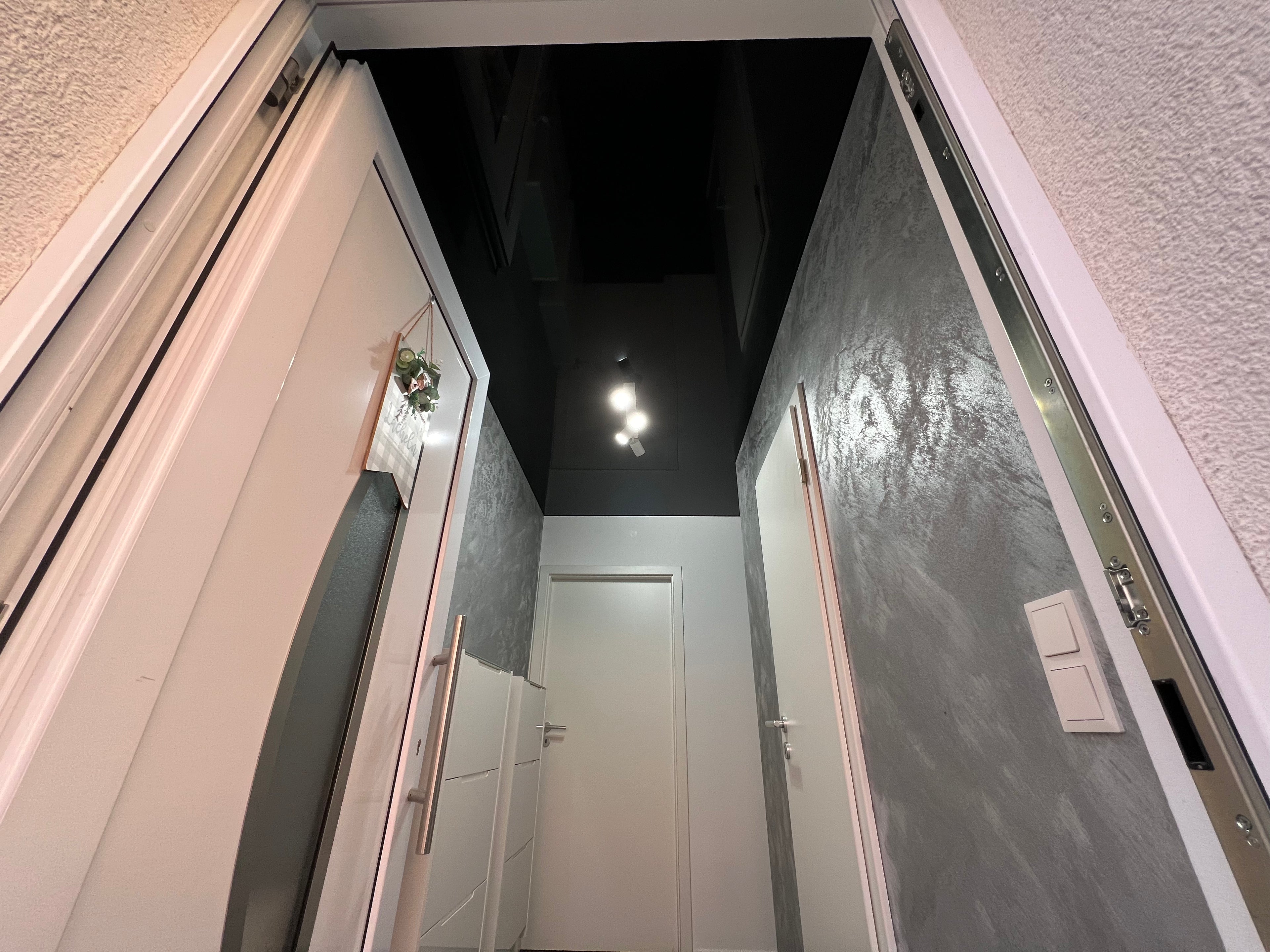 elegante schwarze Spanndecke im Flur in einem modernem Look und einer eingebauten Lampe