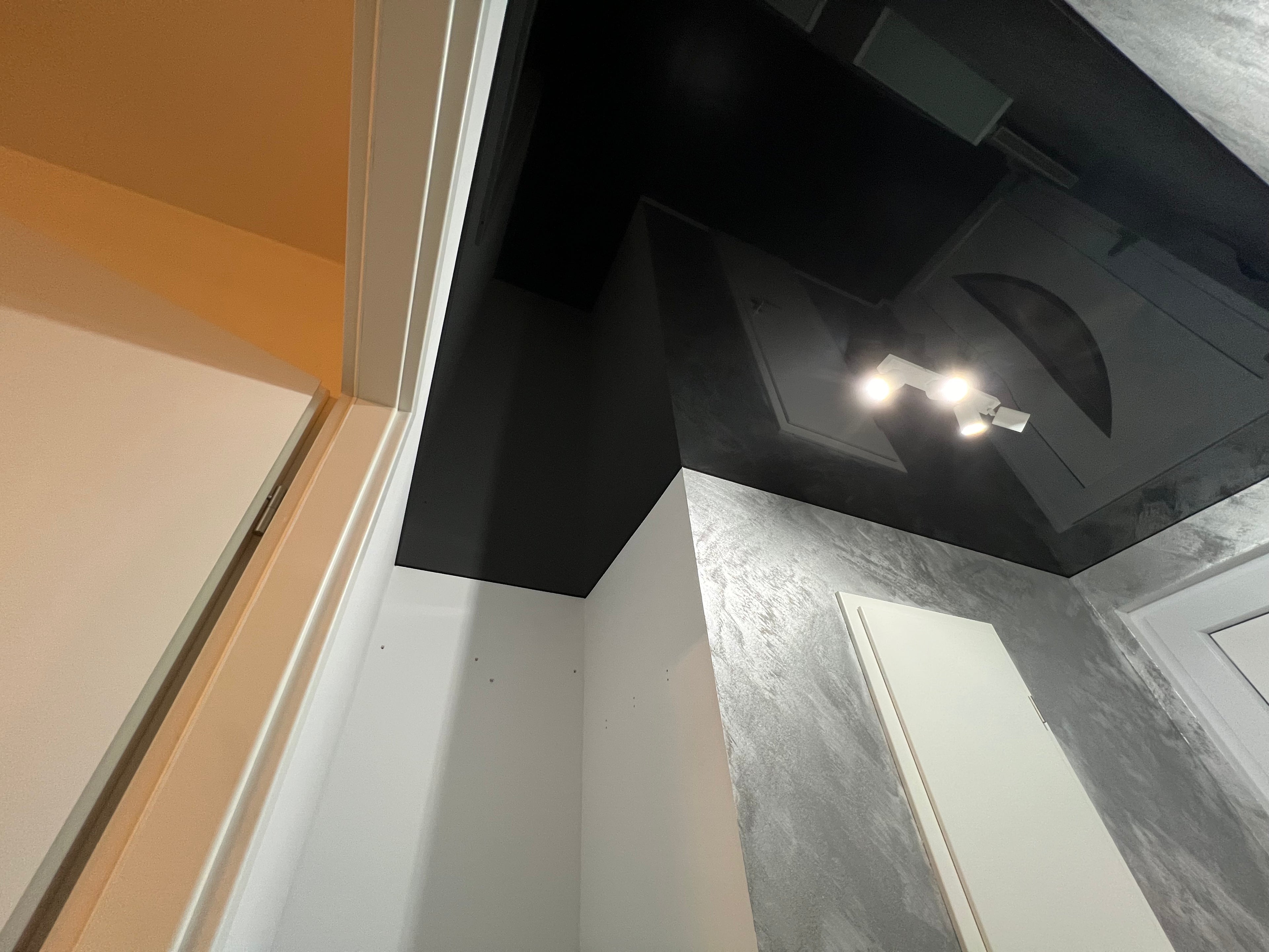 Eine Schwarz glänzende Spanndecke im modernen Look und elegantem Stil mit einer eingebauten Lampe